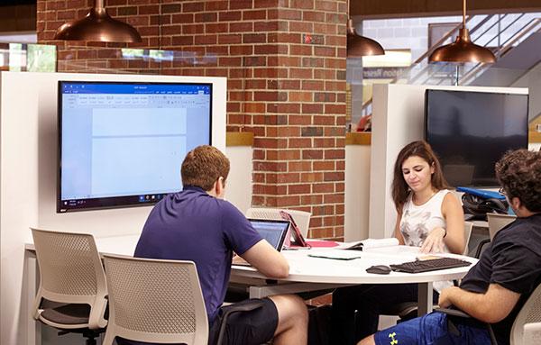 Students working at a 5-person collaboration table in the library.